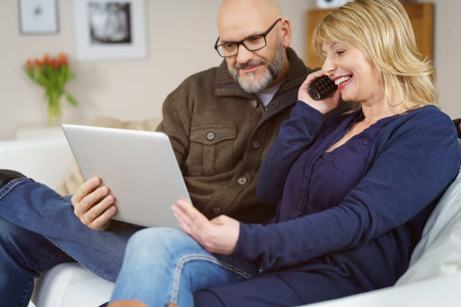 Man and woman holding laptop and on the phone